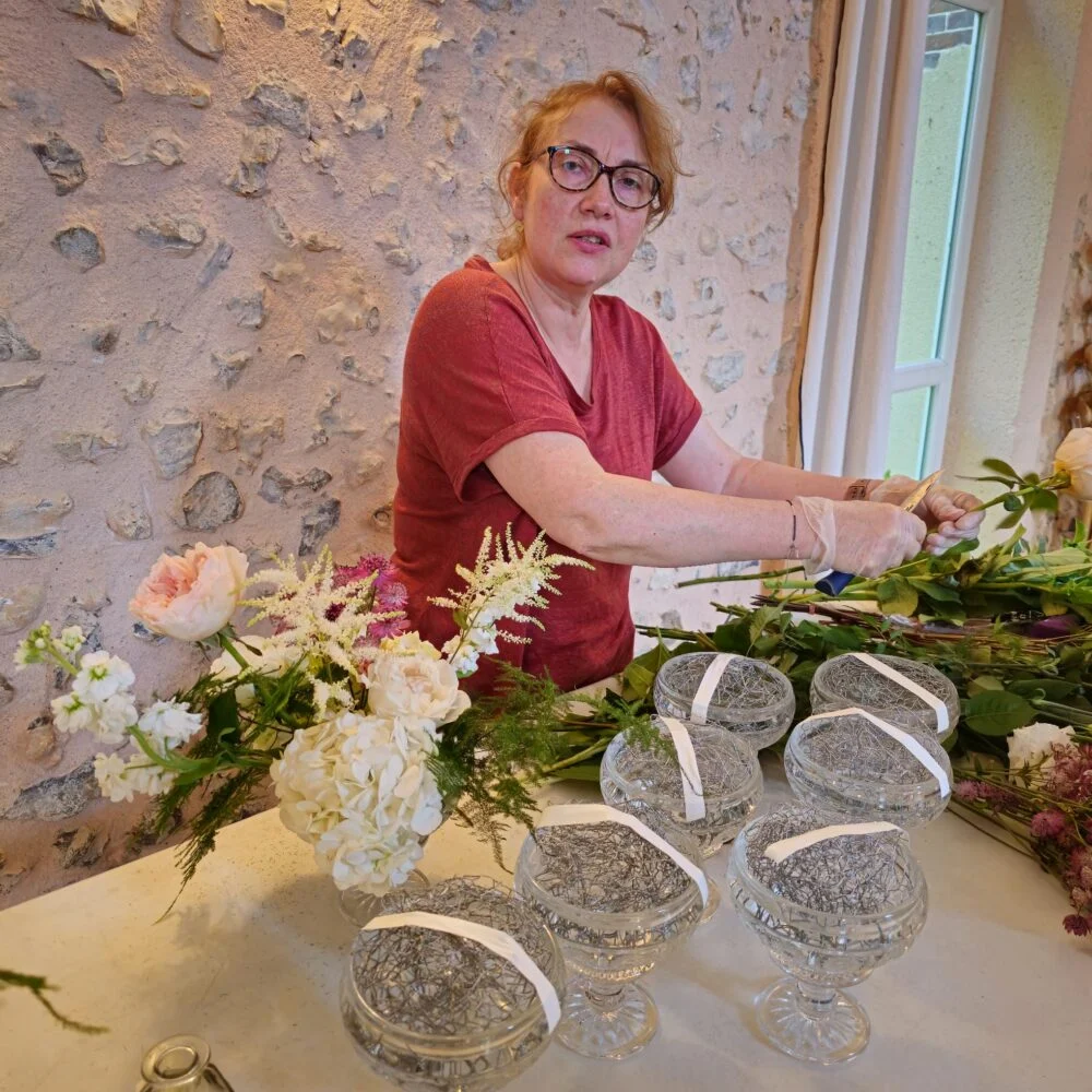 Fleuriste de Camélia Blanc préparant des centres de table pour une réception