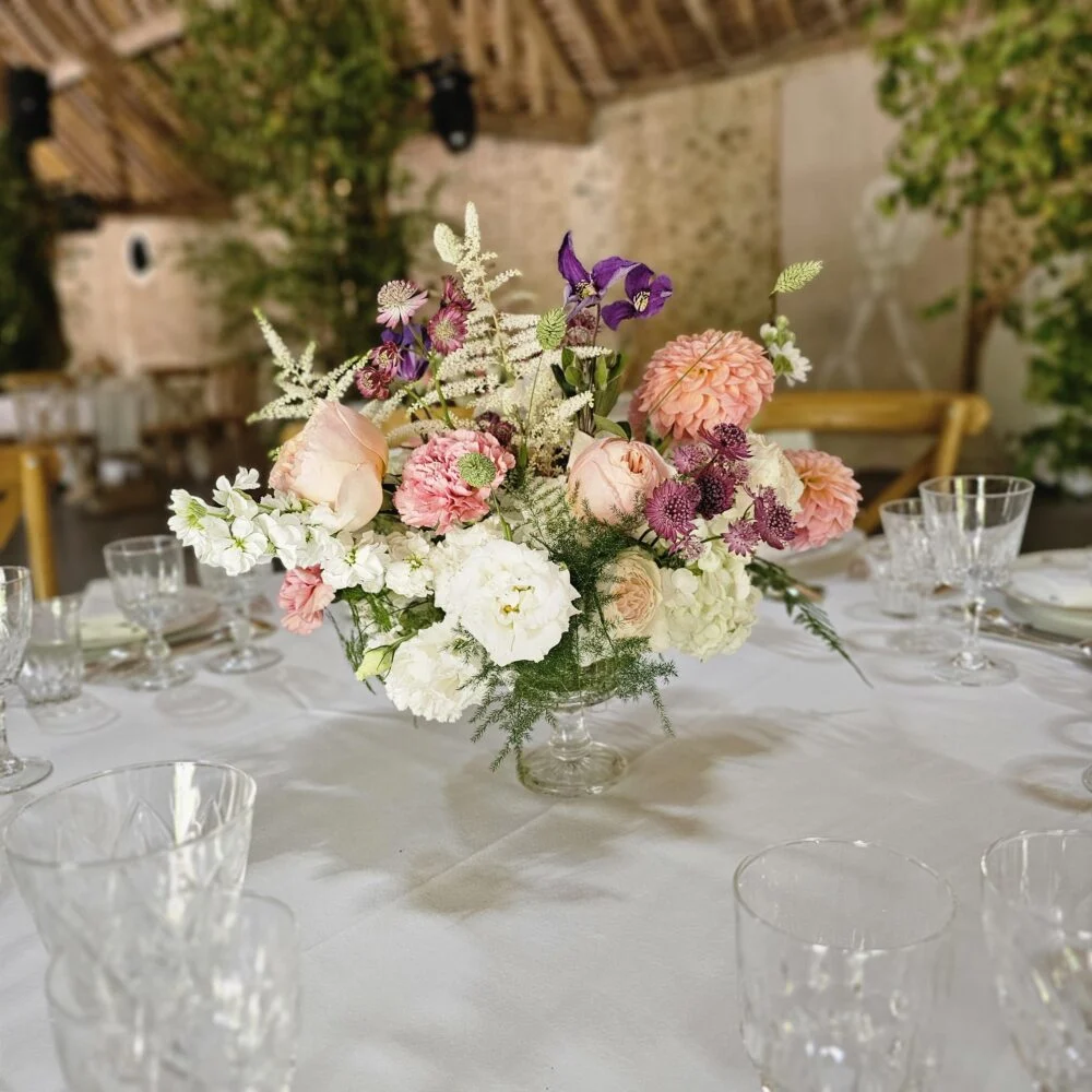 Centre de table de mariage : roses, dahlias et fleurs blanches dans une coupe en verre